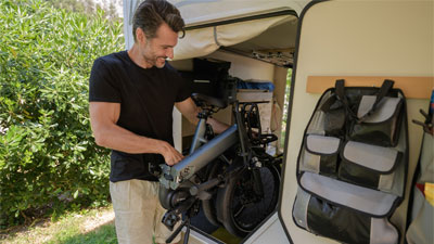 A man stows his folded folding bike in a motorhome.