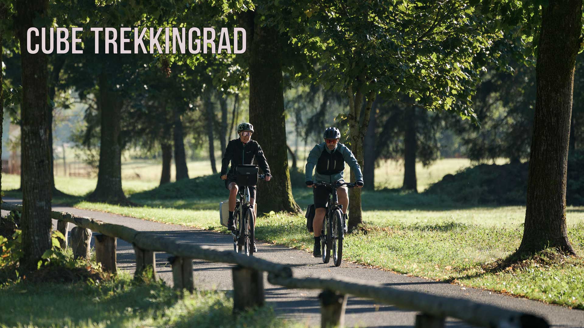The image shows a picture with the caption Cube Trekking Bike. The picture shows a couple riding on a bike path through a park.
