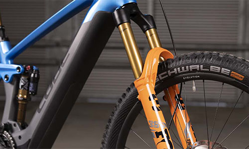 A blue bicycle is shown with a focus on the suspension on the fork.