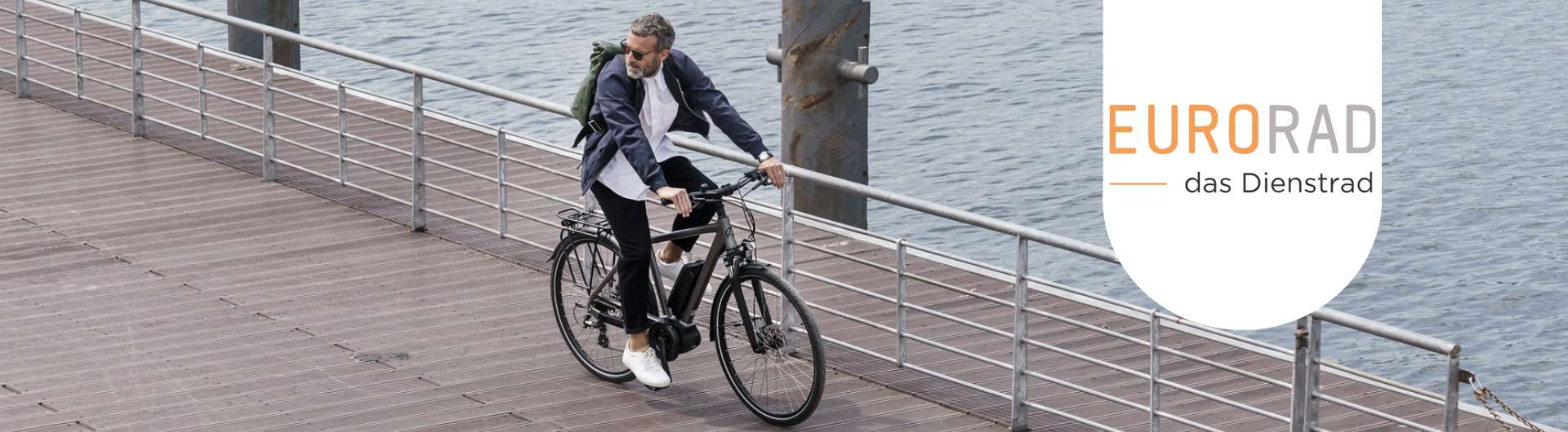 Ein Mann fährt mit seinem E-Bike auf einer Brücke. Neben ihm ist das Eurorad-Logo zu sehen.